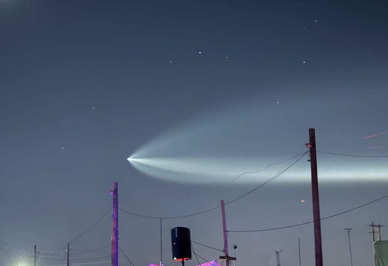 A SpaceX rocket plume in the night sky.