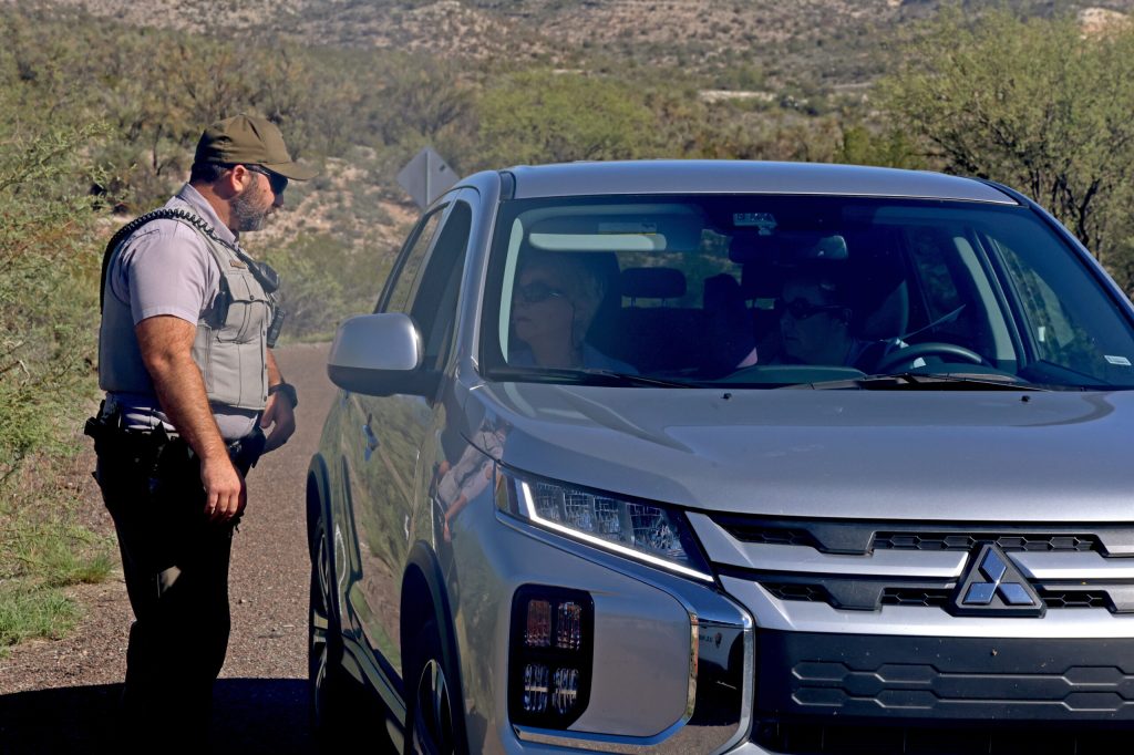 A park ranger talks to people sitting in a car.