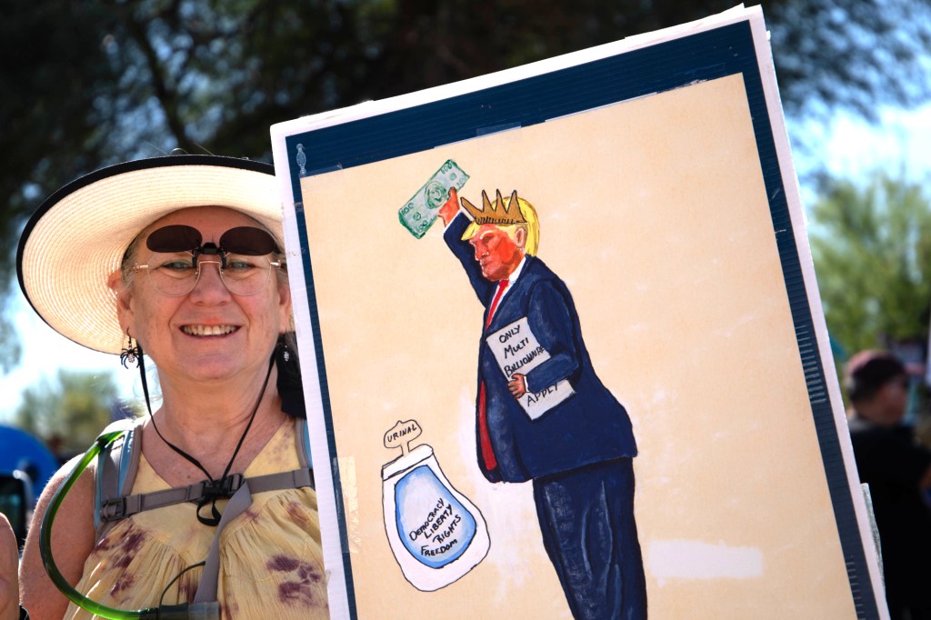 a protester holds a sign of donald trump peeing into a urinal