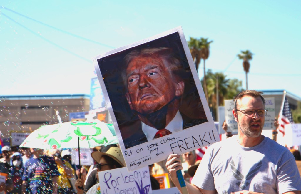 a protester holds a sign featuring donald trump wearing a thong over his neck skin
