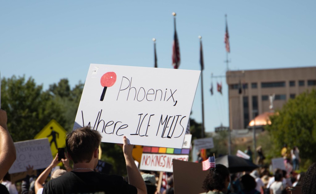 a protester holds a sign that says "Phoenix, where ICE melts"
