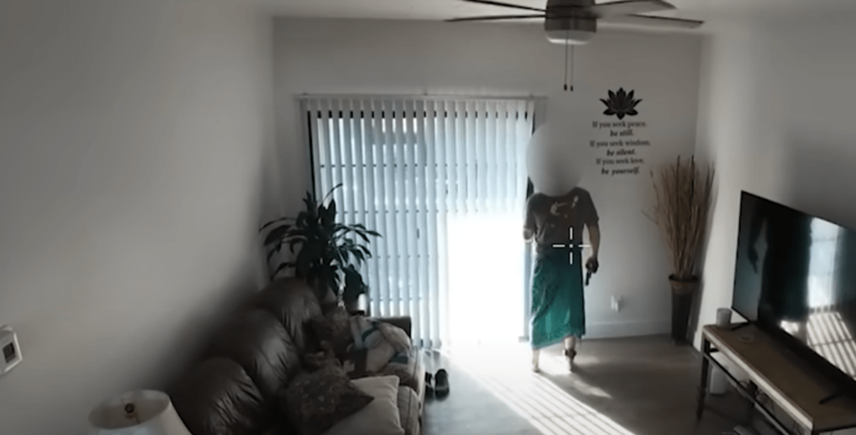 drone footage of a man holding a gun peering out a screen door