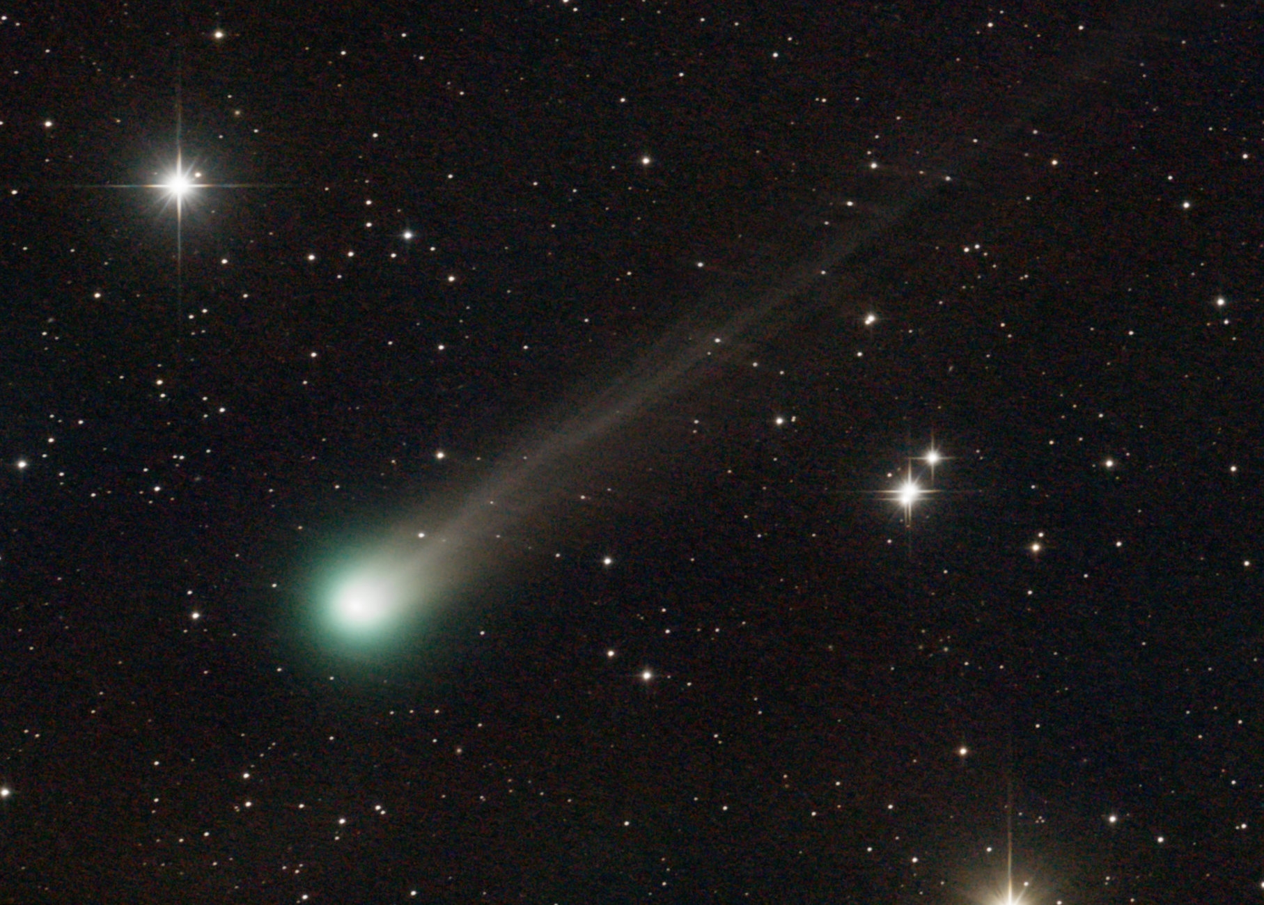 A close-up photo of a green-tinged comet amid the stars.