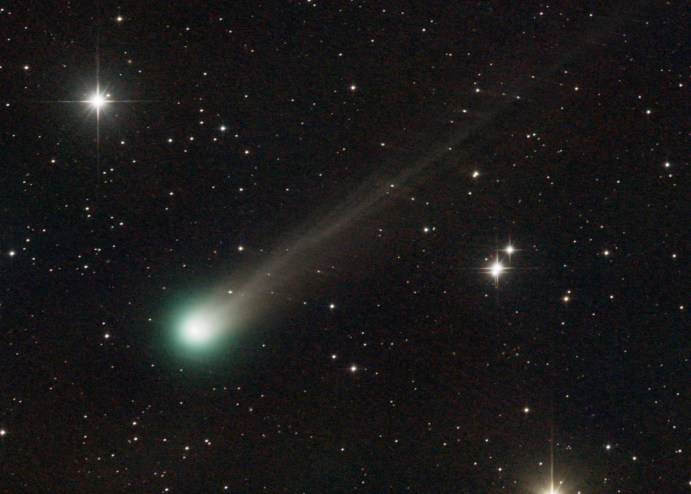 A close-up photo of a green-tinged comet amid the stars.
