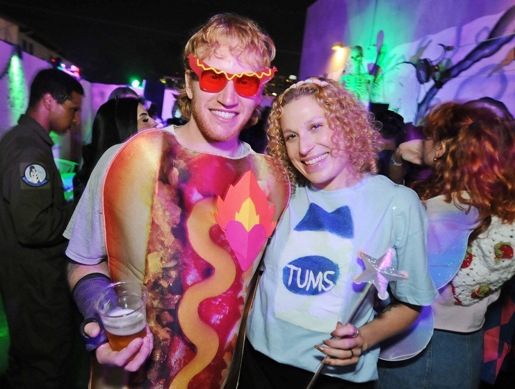 A man dressed in a hot dog costume next to a woman dressed as a fairy.