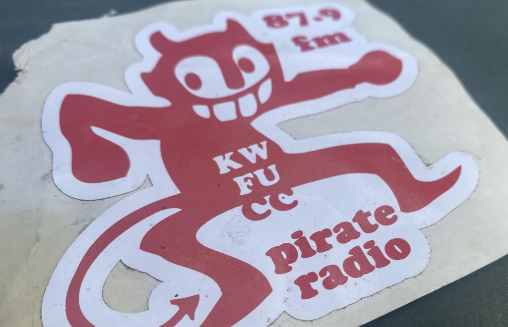 A sticker of a red devil figure with text.