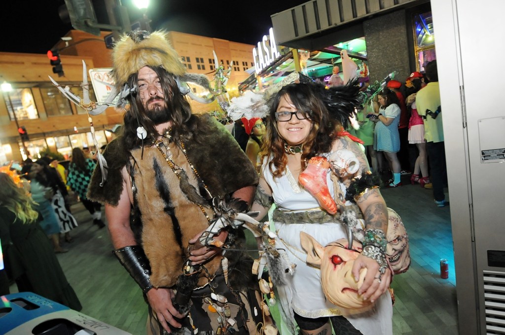 A man and woman dressed in animal furs standing in a downtown area.