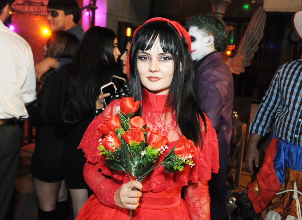 A Latina woman in a red wedding dress holding flowers.