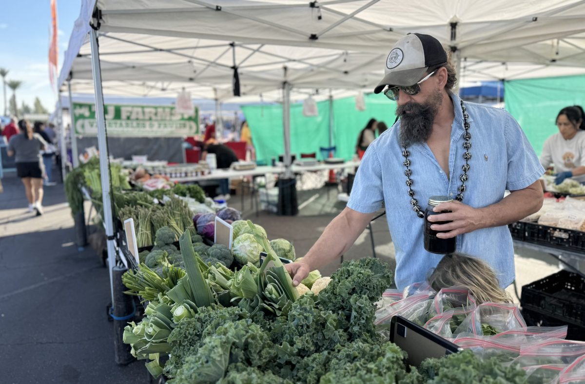 Man browsing greens at a farmers market.