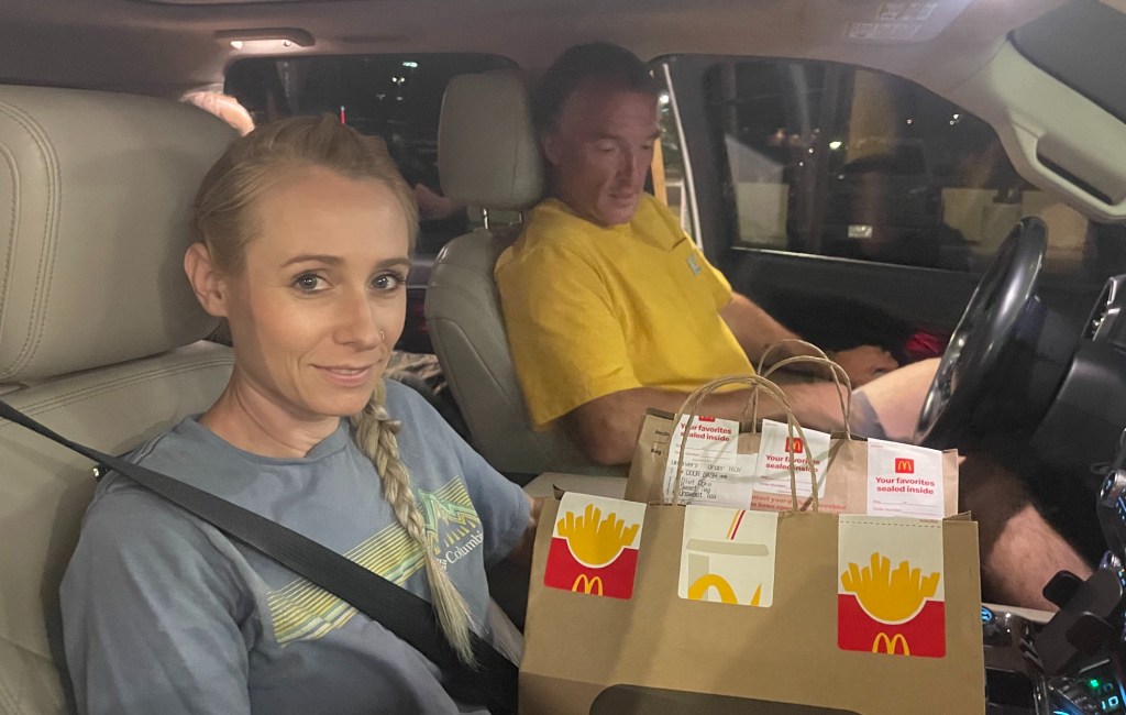 a woman and a man in a car holding mcdonald's bags