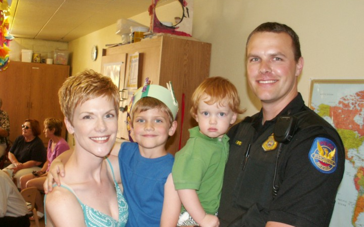 a woman and her police officer husband pose for a photo with their two young boys