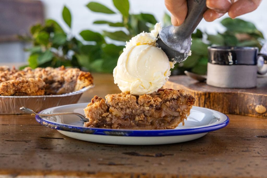 Adding a scoop of ice cream to a slice of pie.
