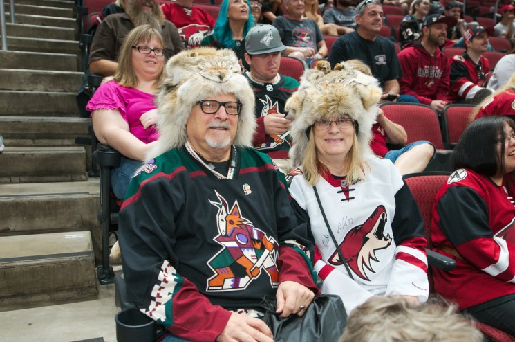Two Arizona Coyotes fans sit in jerseys and custom, furry Coyotes hats.