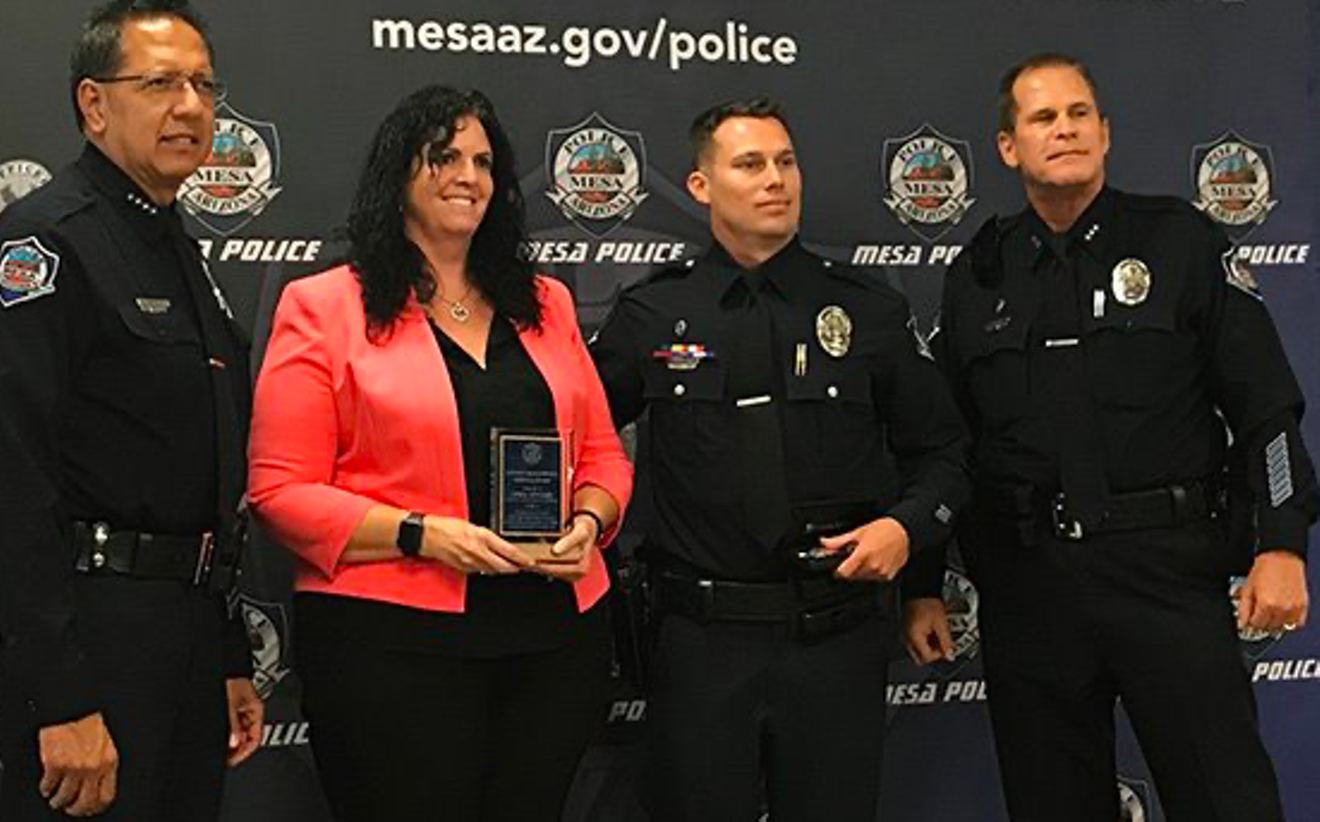 a woman holds an award while posing for a photo with police