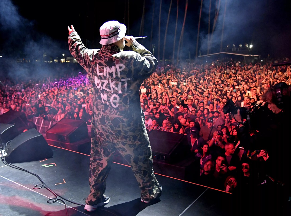 Fred Durst performs onstage to a large crowd of people.