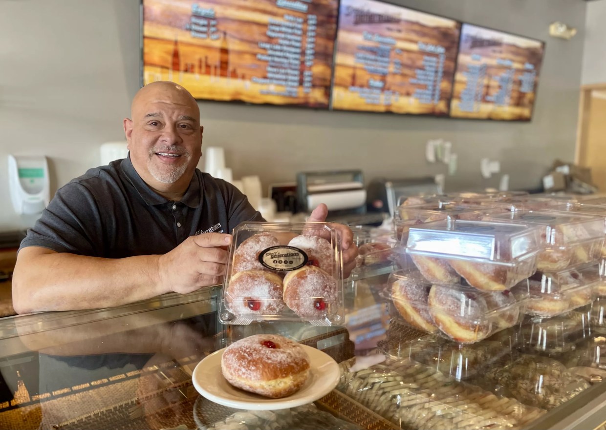 Scott's Generations owner Scott Snyder holds a package of four sufganiyot.