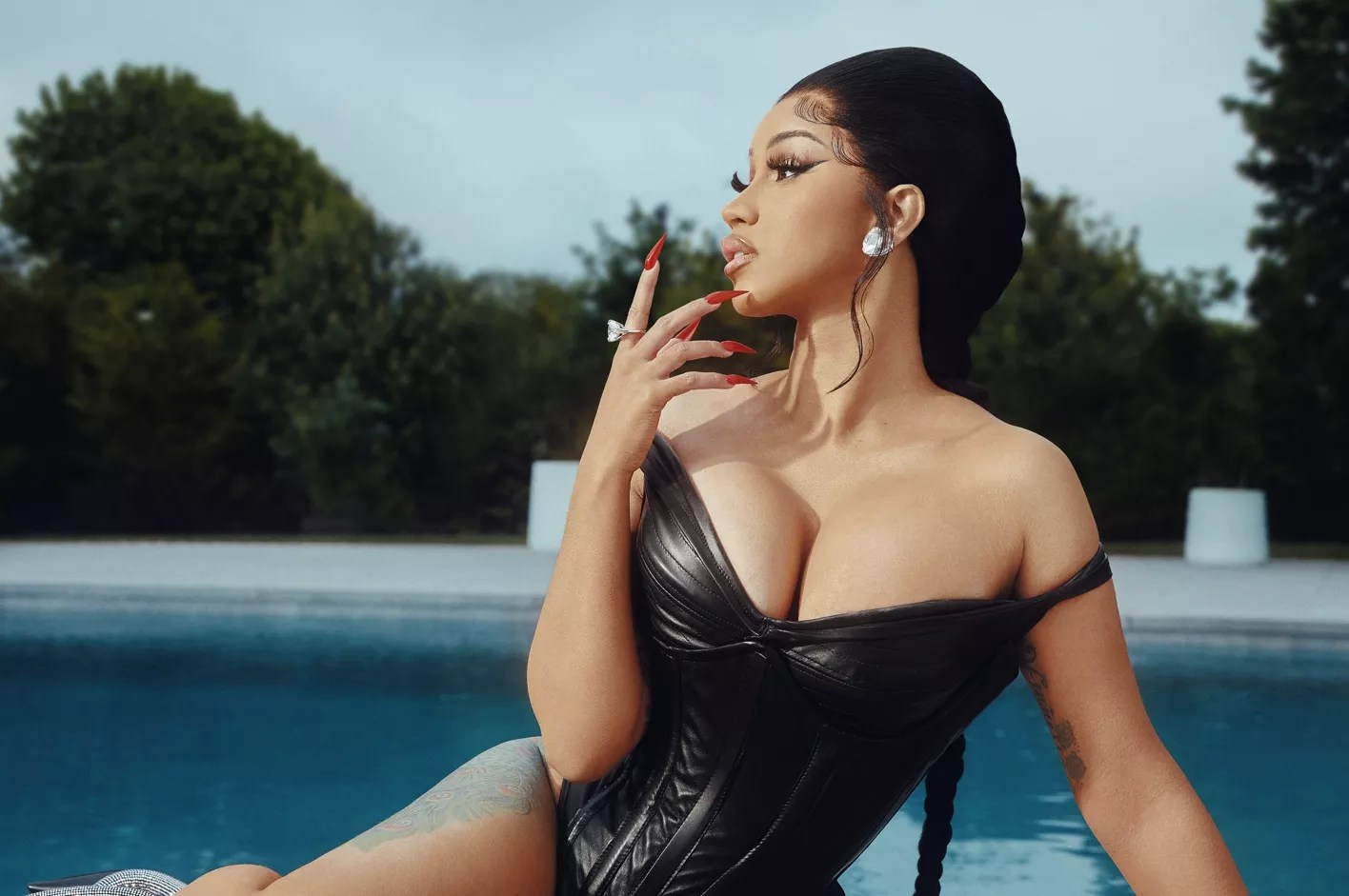 Cardi B in a black dress next to a swimming pool