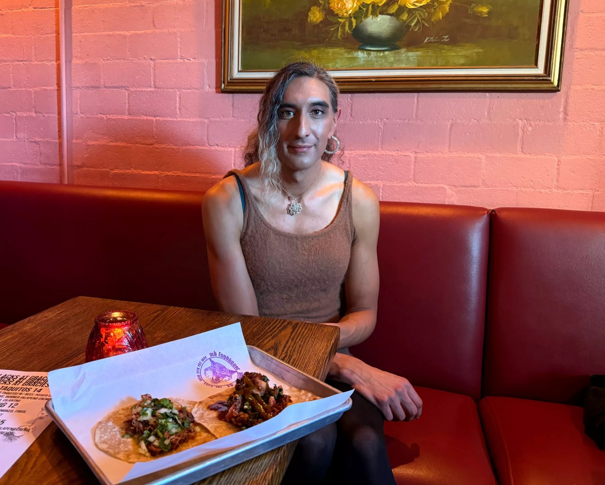 Kristen Martinez sits in a booth with a tray of two tacos.