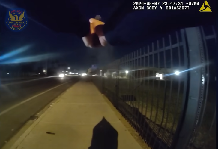 A screenshot from body cam footage showing a police officer's hands gripping a handgun.
