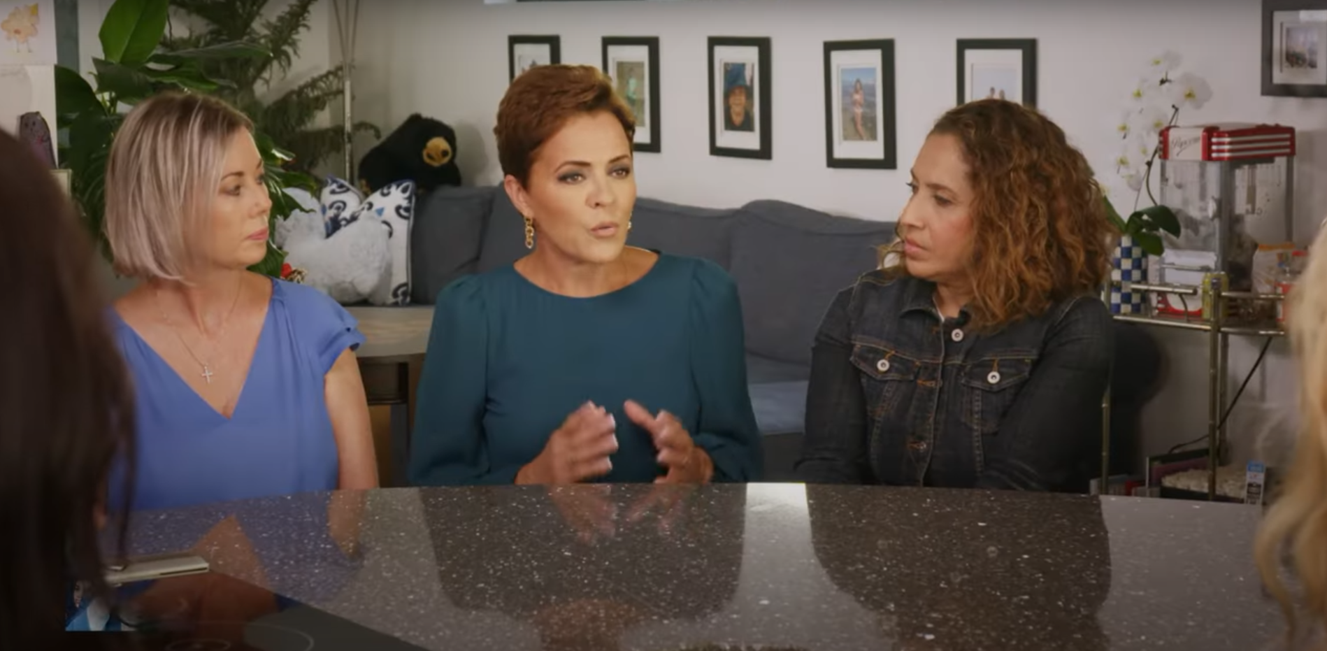 Kari Lake sits at a counter in a suburban home speaking to voters in a campaign ad.