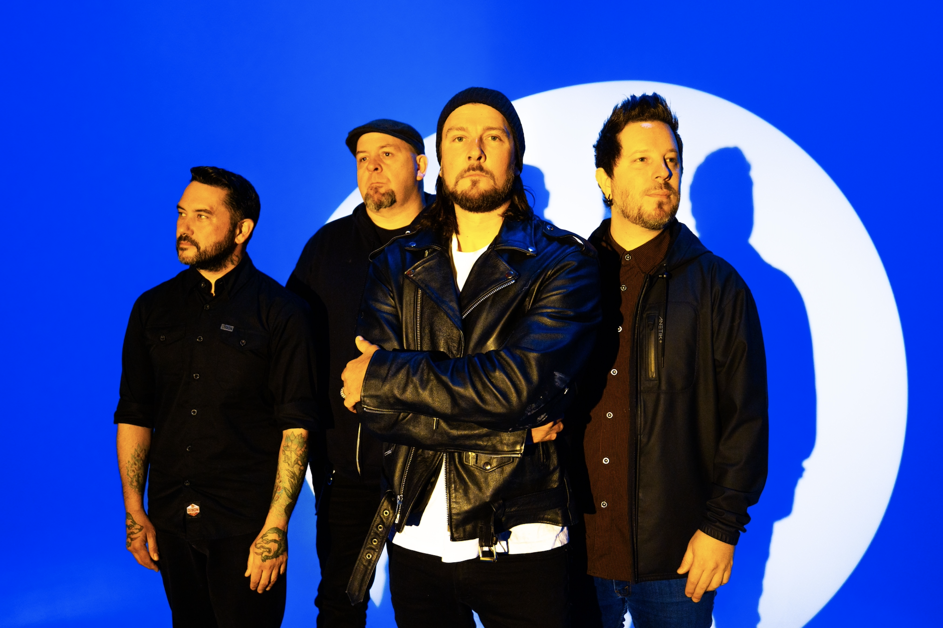 Four men standing in front of a blue and white background.