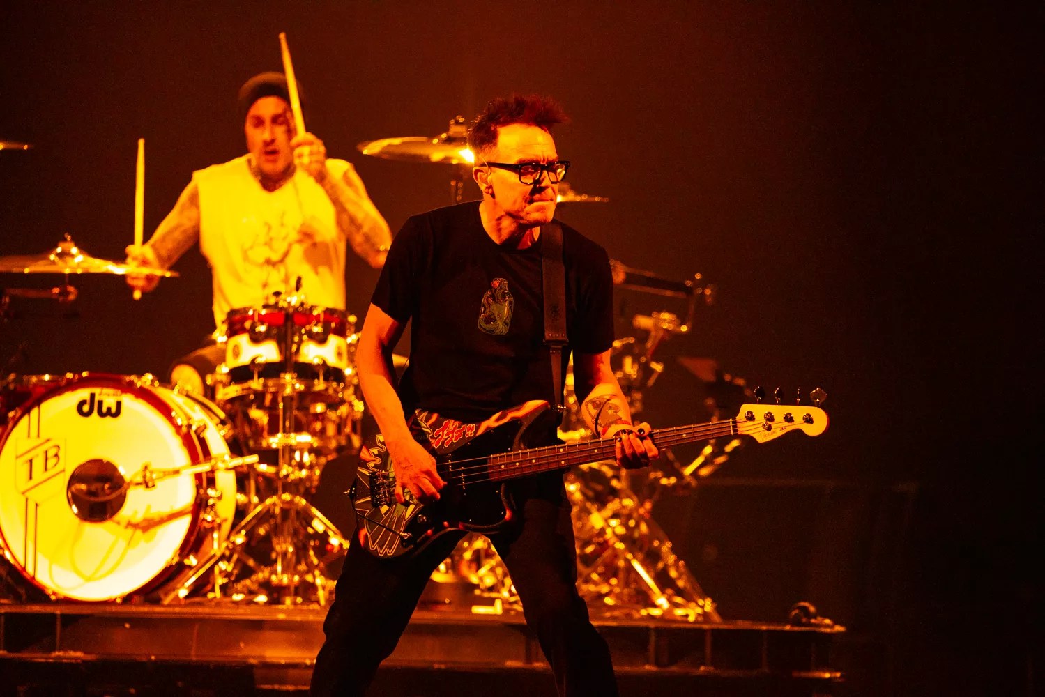 A man playing bass in front of a man playing drums.