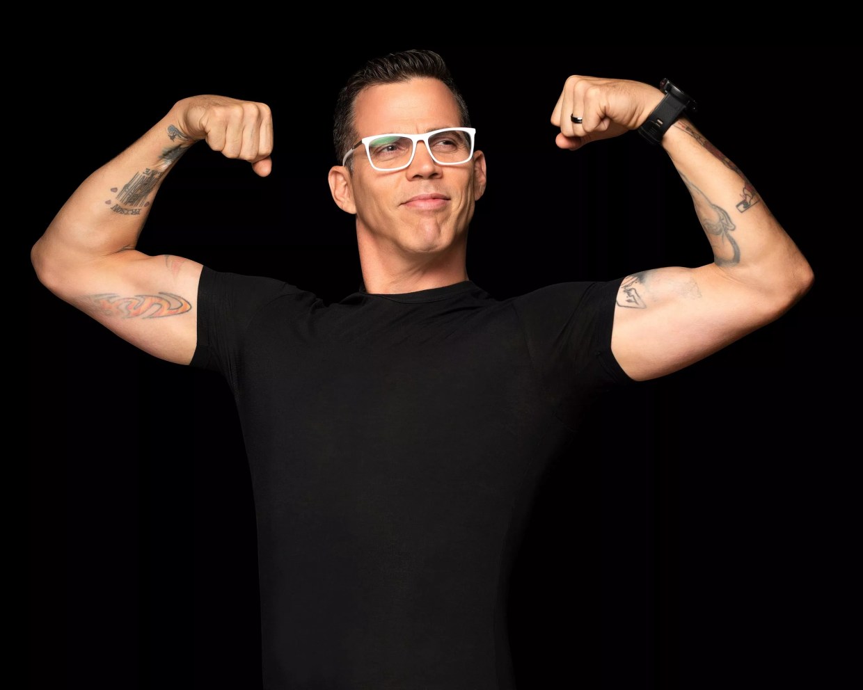 A man on a black background flexing his muscles.