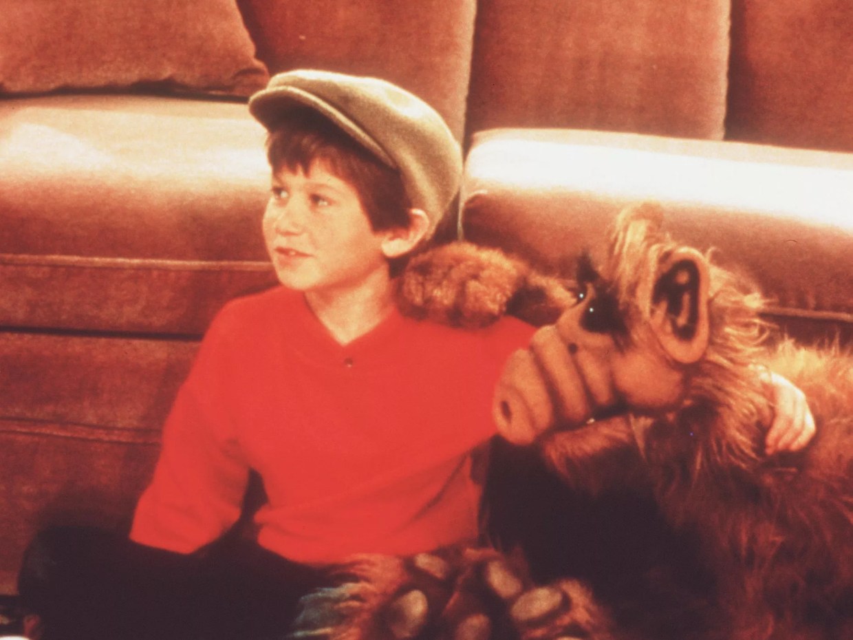 A young boy with an alien puppet.
