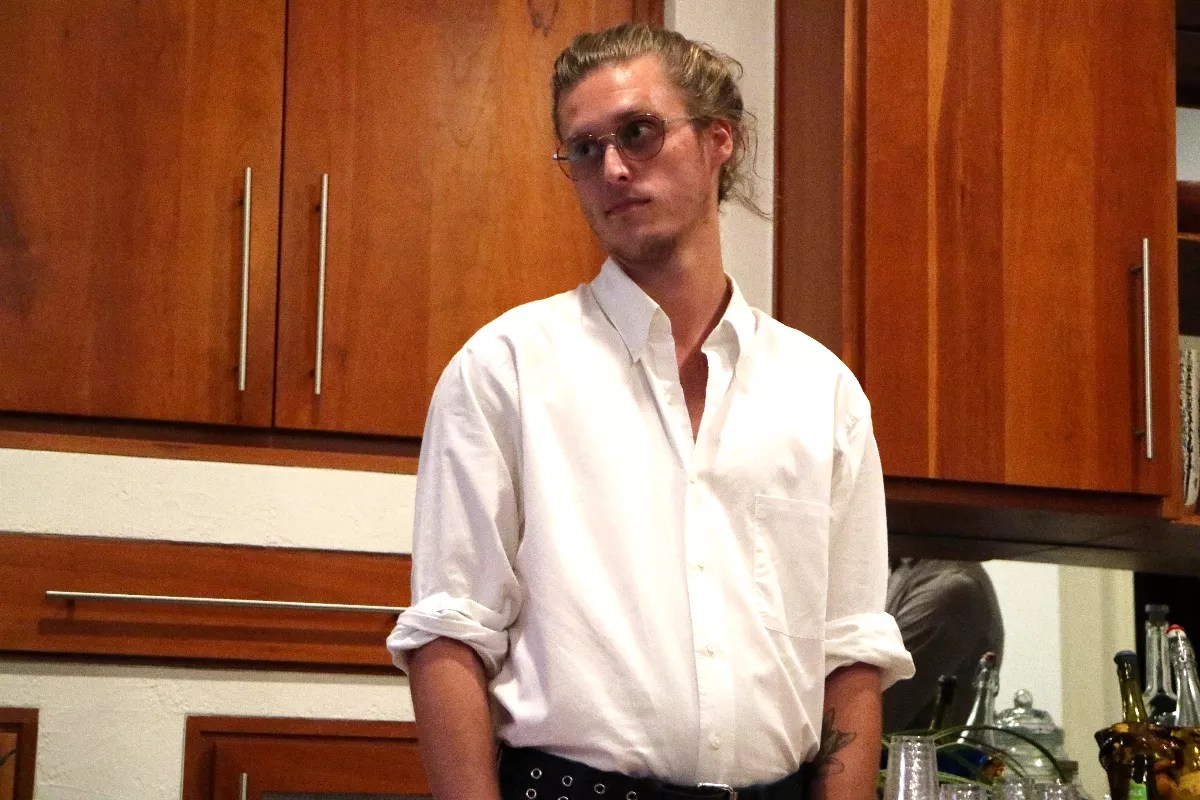 a young man in glasses with his blond hair up in a bun