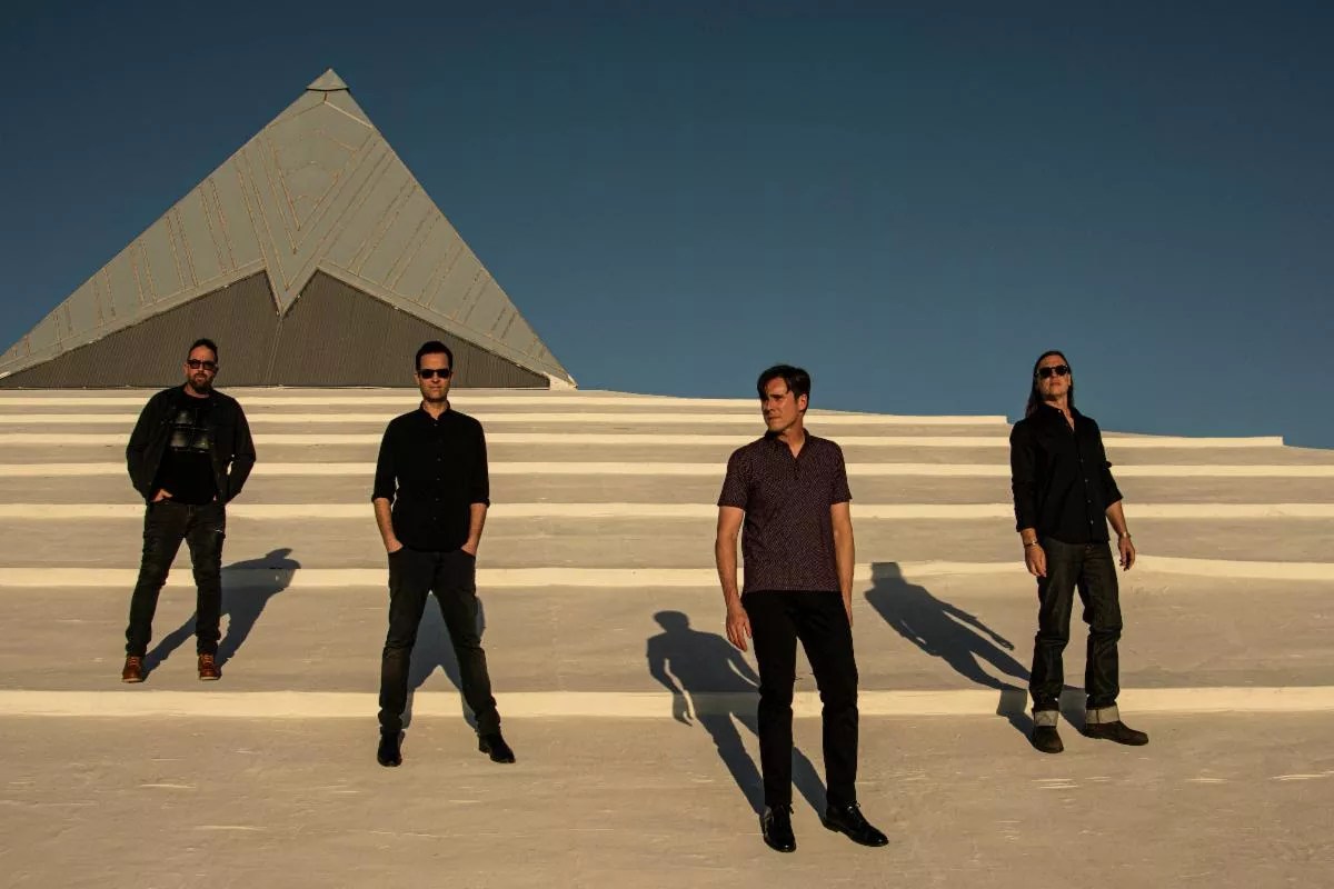 Four men posing on a strange-looking building.