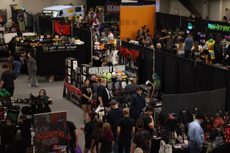 A crowd of people inside the vendor hall of a convention center.