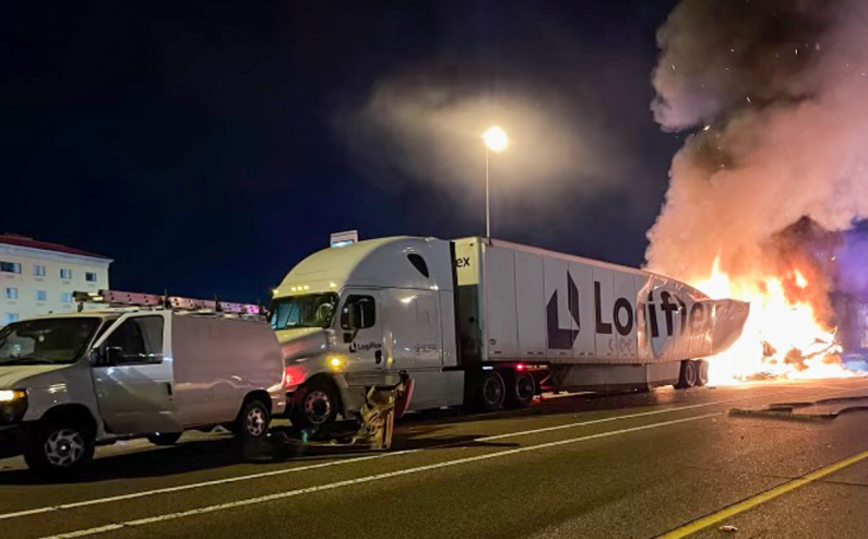 a semi-truck. which is on fire and crashed into another car