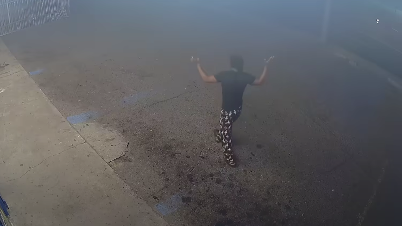 a man in surveillance footage walking with his hands raised