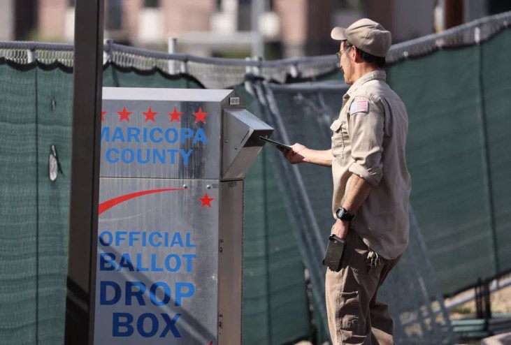 A voter drops his ballot into a drop box at the Maricopa County Tabulation and Election Center