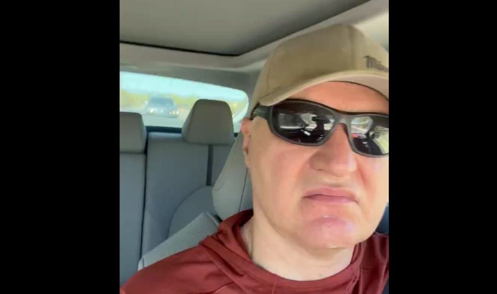 a man in a car wearing sunglasses and a hat