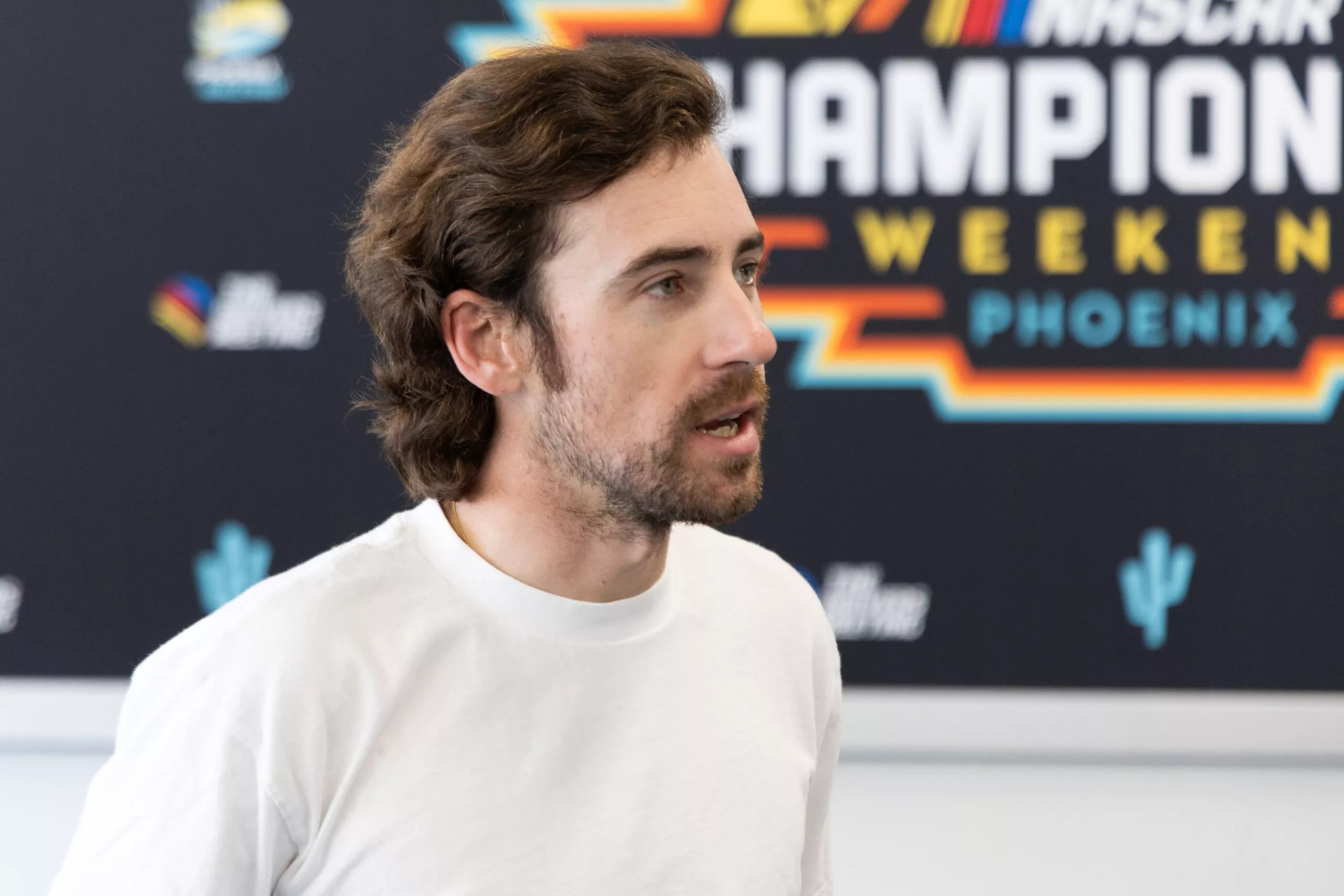 A young man in front of a NASCAR banner.