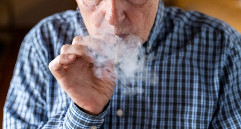 an elderly man smoking a blunt
