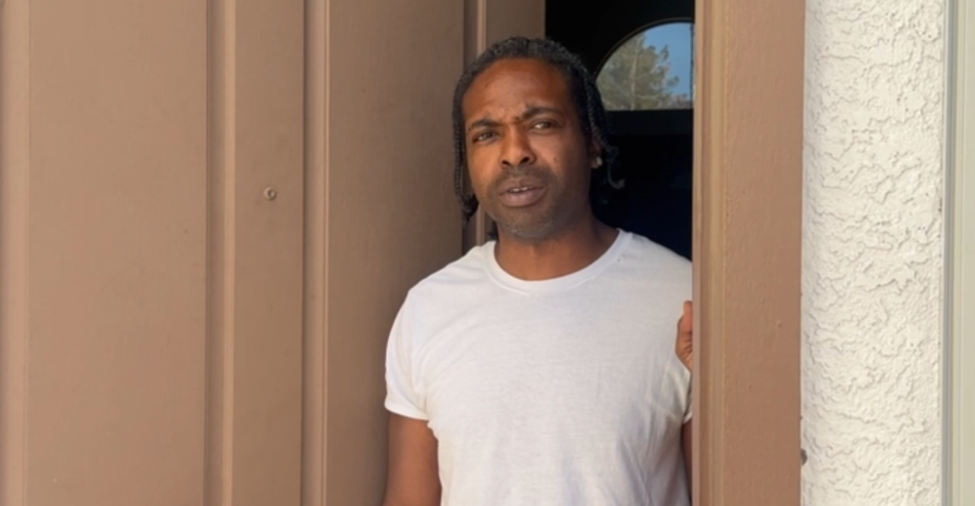 a man in a white shirt standing in an open doorway