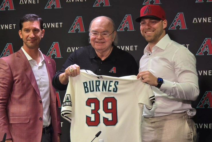 mike hazen and ken kendrick hand a diamondbacks jersey to corbin burnes