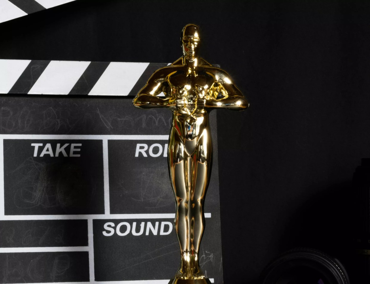 An Academy Award in front of a film slate.