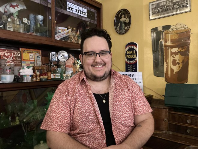 a man with black hair and glasses smiles