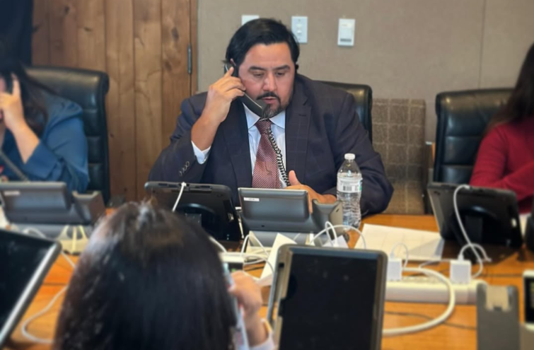 a man at a conference table speaks on the phone