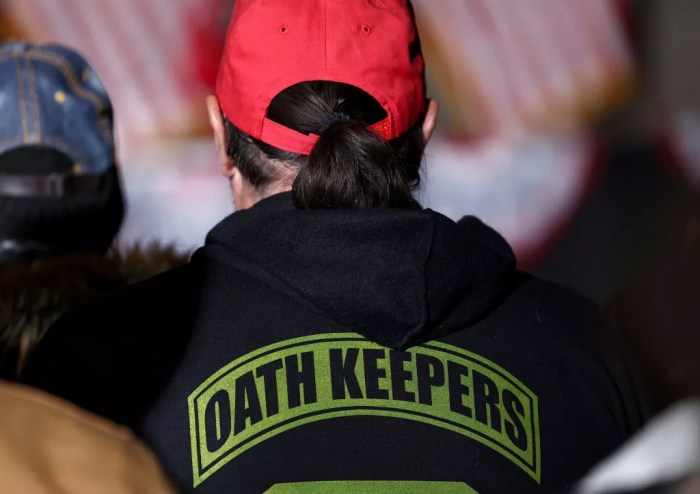 a person seen from behind in a red hat and "oath keepers" sweatshirt