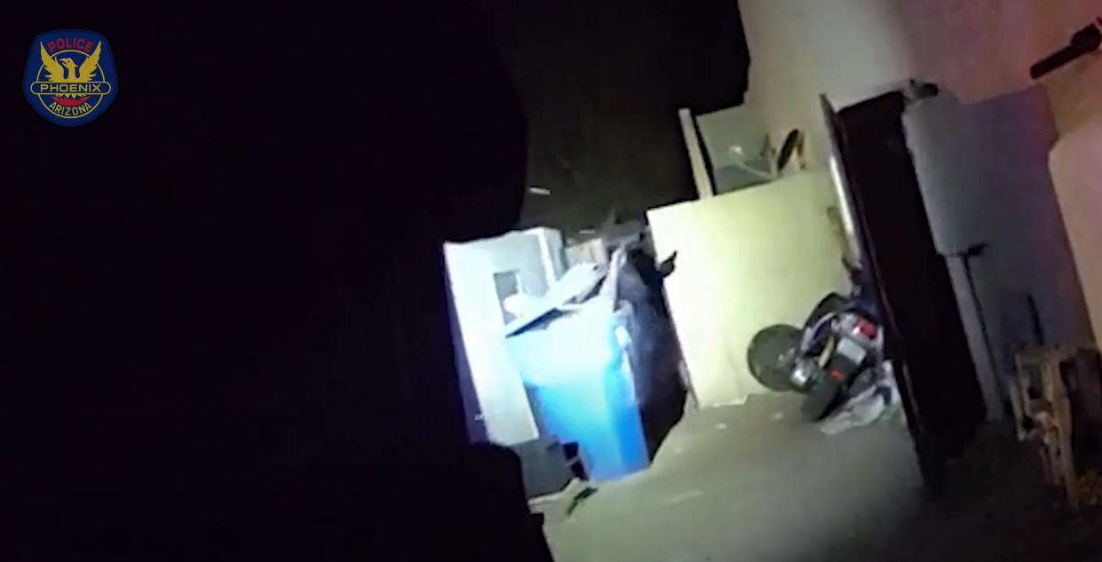 body-cam footage at night of a hand holding something popping out of a blue recycling bin