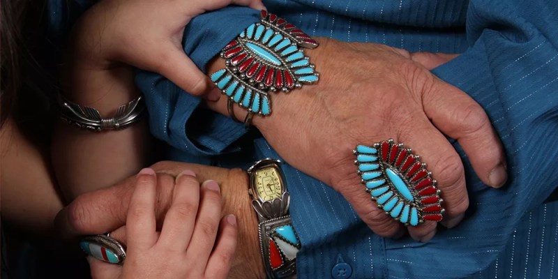 young and old native american hands holding each other, with turquoise jewelry
