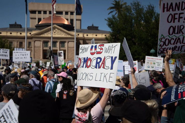 protesters at the arizona capitol. one sign says "show us what democracy looks like"