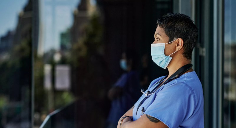 a health worker in a mask stares into the distance