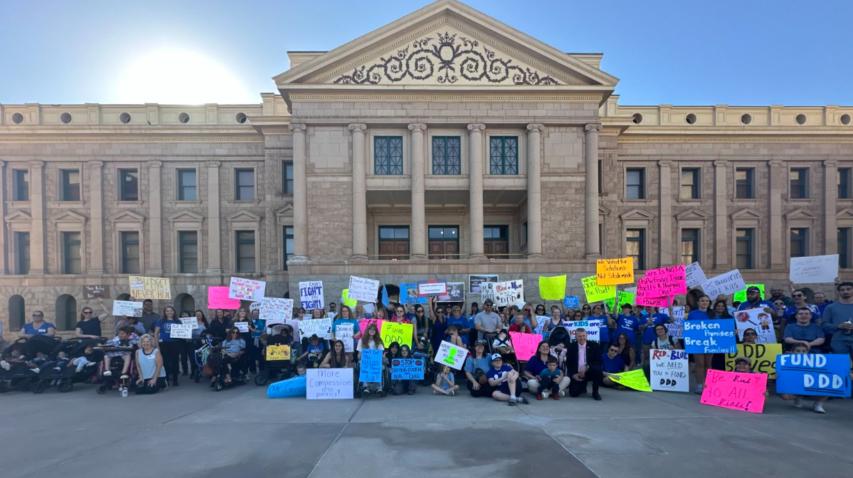 people in front of the arizona capitol holding signs