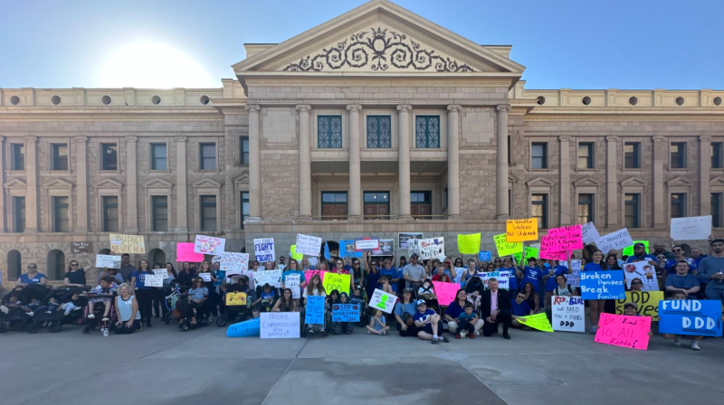 people in front of the arizona capitol holding signs