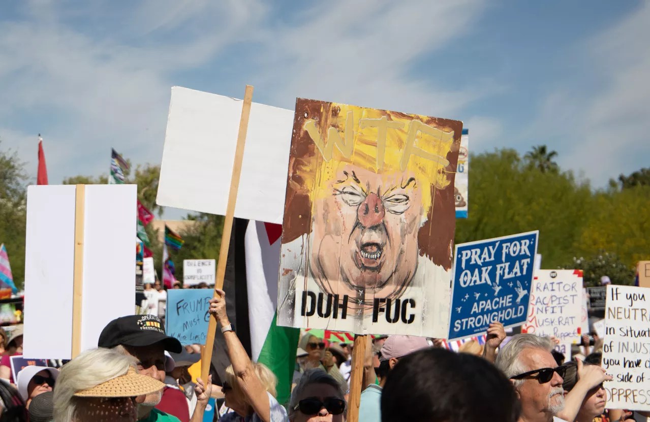 a protest sign with donald trump painted a bit like a pig, with the words "duh fuc"